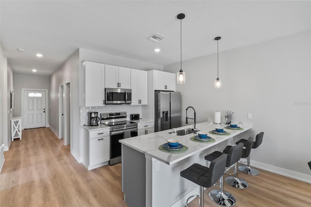 9155 Agate St, Port Charlotte, FL 33981 - kitchen featuring stainless steel appliances, a kitchen breakfast bar, a peninsula, light wood-style flooring, and white cabinets