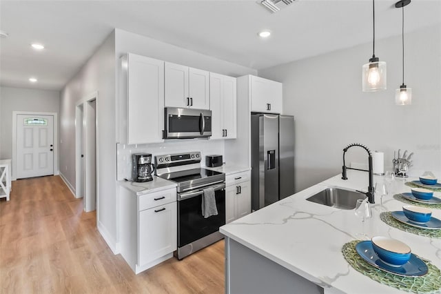 9155 Agate St, Port Charlotte, FL 33981 - kitchen featuring stainless steel appliances, light wood finished floors, light stone counters, white cabinetry, and decorative light fixtures