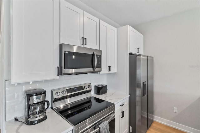 9155 Agate St, Port Charlotte, FL 33981 - kitchen featuring stainless steel appliances, light stone countertops, and white cabinetry