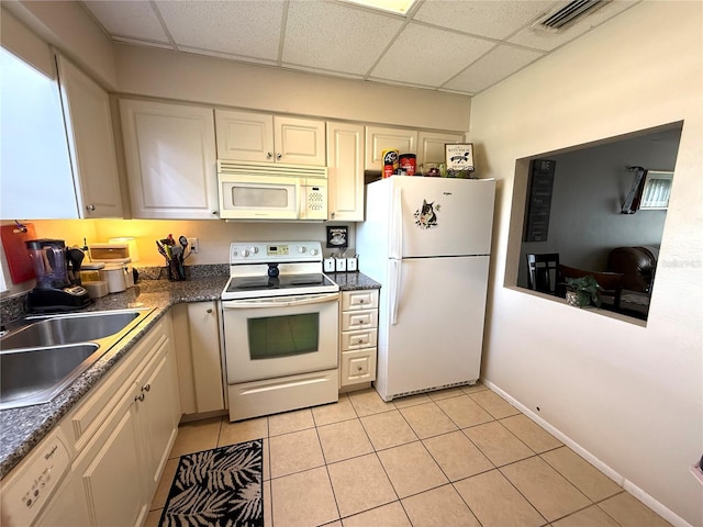 3116 Harbor Blvd Unit 3B, Port Charlotte, FL 33952 - kitchen with white appliances, a drop ceiling, dark countertops, light tile patterned floors, and white cabinets