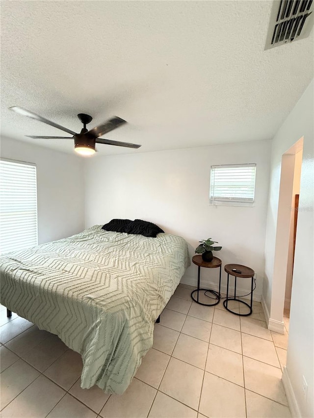 24 Charwood Cir, Lehigh Acres, FL 33936 - bedroom with light tile patterned flooring, a textured ceiling, and a ceiling fan