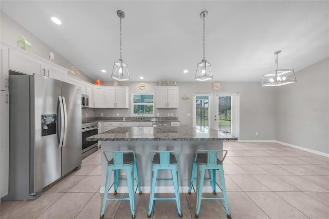 12112 Helios Ave, Port Charlotte, FL 33981 - kitchen featuring stainless steel appliances, light tile patterned floors, a breakfast bar area, white cabinets, and a center island