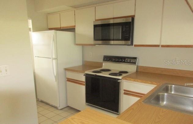 429 Cerromar Ln Unit 353, Venice, FL 34293 - kitchen with white appliances, light countertops, light tile patterned floors, and cream cabinetry