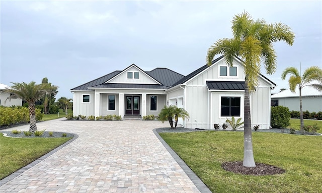 2073 Treasure Ln, Punta Gorda, FL 33982 - modern farmhouse with board and batten siding, a standing seam roof, decorative driveway, and a front yard
