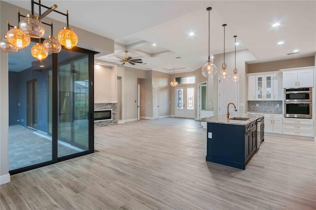 4026 Vasco St, Punta Gorda, FL 33950 - kitchen featuring double oven, light wood finished floors, tasteful backsplash, open floor plan, and white cabinetry