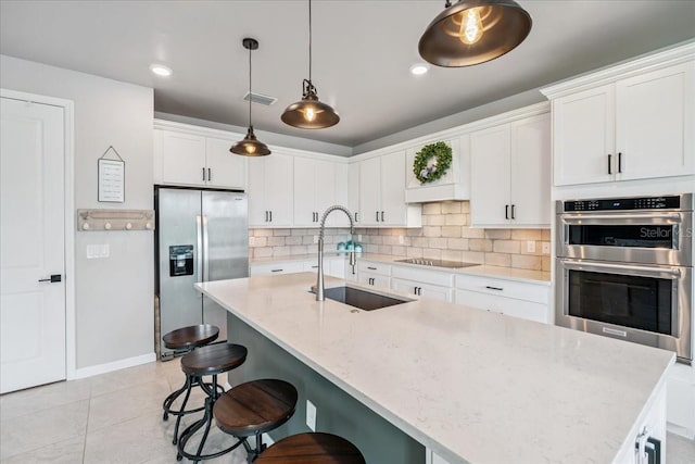 2596 Buckthorn Loop, North Port, FL 34289 - kitchen with appliances with stainless steel finishes, decorative backsplash, a kitchen bar, white cabinetry, and light tile patterned floors