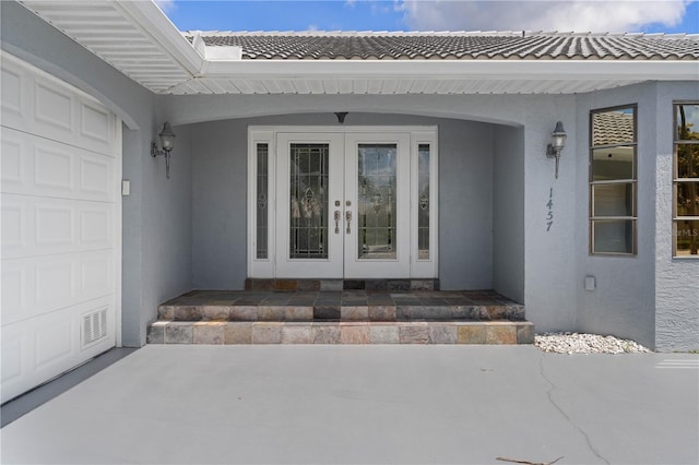 1457 Sea Fan Dr, Punta Gorda, FL 33950 - doorway to property featuring french doors, stucco siding, a tile roof, and an attached garage