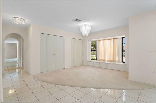 1457 Sea Fan Dr, Punta Gorda, FL 33950 - unfurnished bedroom featuring light carpet, multiple closets, arched walkways, and light tile patterned floors
