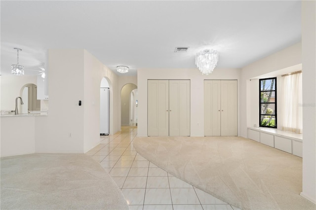 1457 Sea Fan Dr, Punta Gorda, FL 33950 - unfurnished bedroom featuring arched walkways, multiple closets, light carpet, light tile patterned flooring, and a chandelier