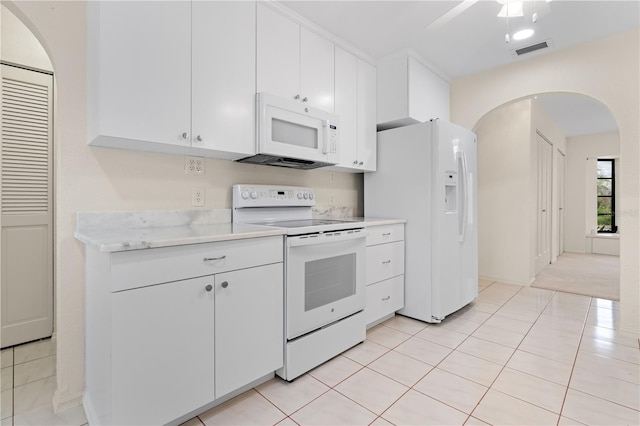 1457 Sea Fan Dr, Punta Gorda, FL 33950 - kitchen with white appliances, light countertops, light tile patterned floors, arched walkways, and white cabinetry