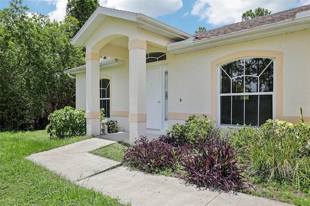5260 Jessamine Ave, North Port, FL 34291 - doorway to property with stucco siding, a yard, and roof with shingles