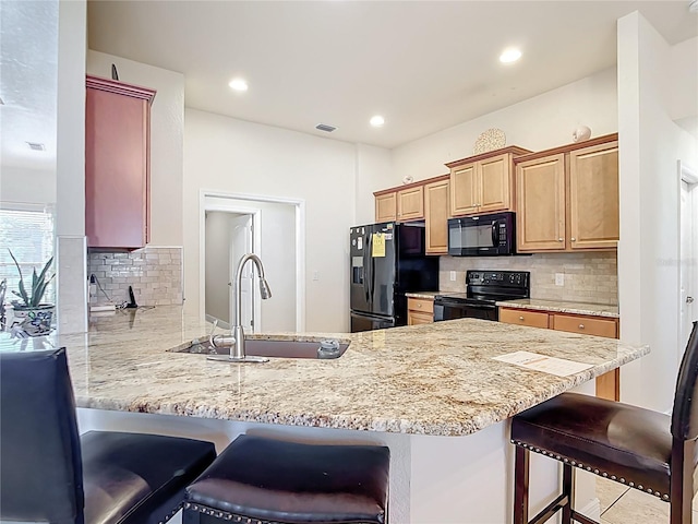 1323 Algiers St, Punta Gorda, FL 33980 - kitchen with black appliances, a peninsula, decorative backsplash, a kitchen bar, and light stone countertops