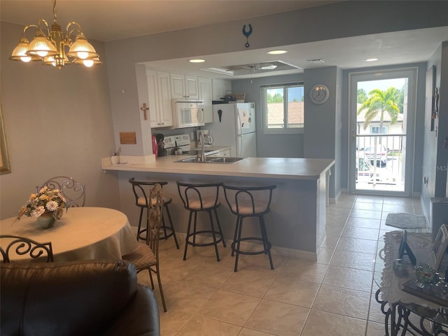 25275 Rampart Blvd Unit 207, Punta Gorda, FL 33983 - kitchen featuring white appliances, a peninsula, light tile patterned floors, a breakfast bar area, and recessed lighting