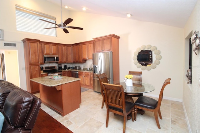 25188 Marion Ave Unit 24, Punta Gorda, FL 33950 - kitchen with stainless steel appliances, ceiling fan, a center island, brown cabinetry, and light stone counters