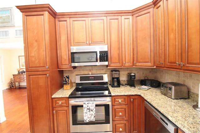 25188 Marion Ave Unit 24, Punta Gorda, FL 33950 - kitchen featuring appliances with stainless steel finishes, decorative backsplash, light stone countertops, and brown cabinets