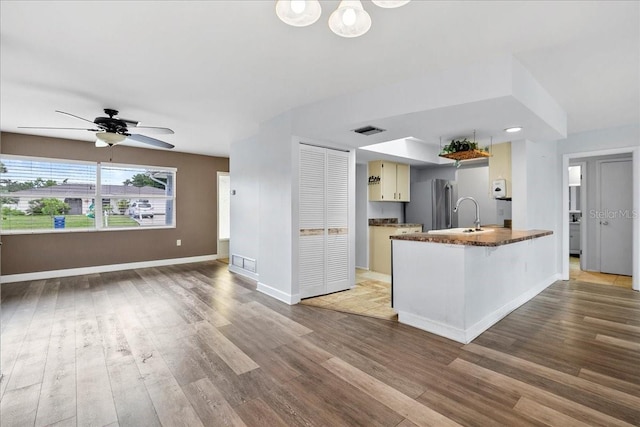 572 Darwin Rd, Venice, FL 34293 - kitchen featuring dark countertops, wood finished floors, a peninsula, ceiling fan, and a kitchen bar