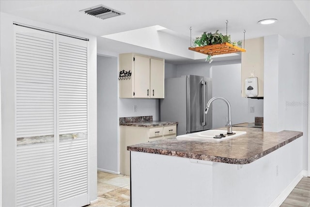 572 Darwin Rd, Venice, FL 34293 - kitchen featuring freestanding refrigerator, a peninsula, dark countertops, a kitchen breakfast bar, and a raised ceiling