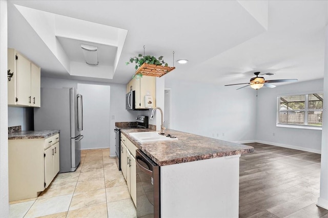 572 Darwin Rd, Venice, FL 34293 - kitchen featuring stainless steel appliances, dark countertops, a ceiling fan, and a tray ceiling