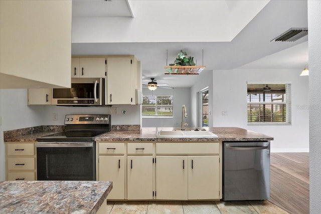572 Darwin Rd, Venice, FL 34293 - kitchen featuring stainless steel appliances, cream cabinets, a peninsula, and dark countertops