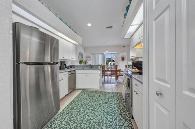 860 Silver Springs Ter NW, Port Charlotte, FL 33948 - kitchen with stainless steel appliances, white cabinets, light tile patterned floors, a peninsula, and recessed lighting