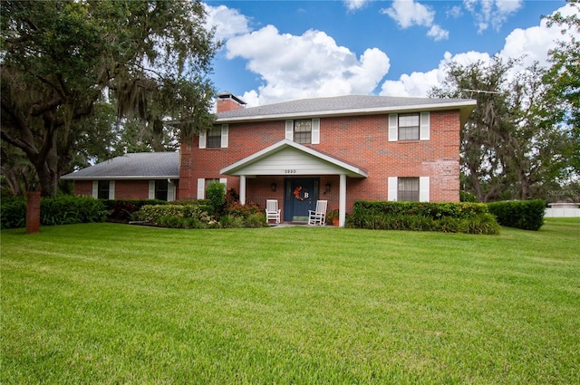 3990 NE Ashley Ter, Arcadia, FL 34266 - view of front of house with a front yard, brick siding, a chimney, and a porch