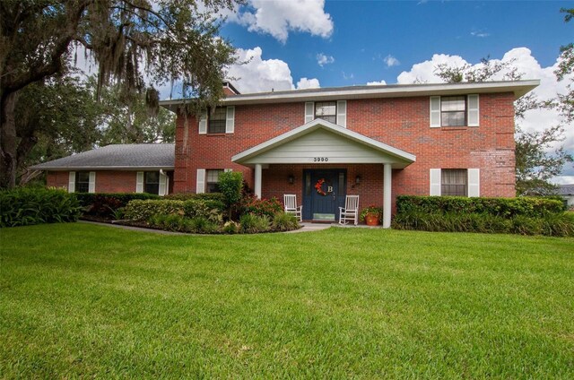 3990 NE Ashley Ter, Arcadia, FL 34266 - view of front of property featuring brick siding, a front lawn, and covered porch