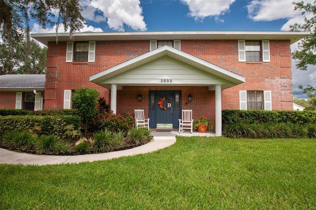 3990 NE Ashley Ter, Arcadia, FL 34266 - view of front of house featuring a front yard, brick siding, and covered porch