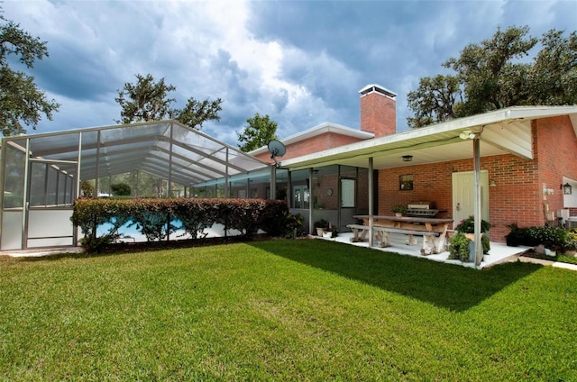 3990 NE Ashley Ter, Arcadia, FL 34266 - rear view of house with brick siding, a chimney, a yard, a lanai, and a patio area