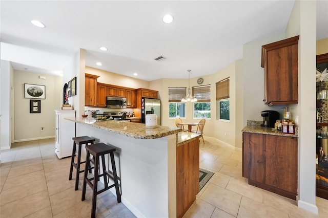 2697 Parrot St, North Port, FL 34286 - kitchen featuring appliances with stainless steel finishes, light tile patterned flooring, a kitchen bar, light stone countertops, and recessed lighting