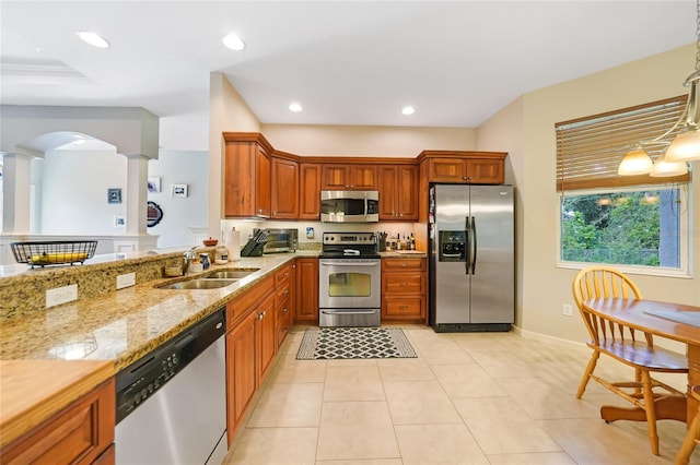 2697 Parrot St, North Port, FL 34286 - kitchen with stainless steel appliances, light stone countertops, brown cabinetry, decorative columns, and light tile patterned floors