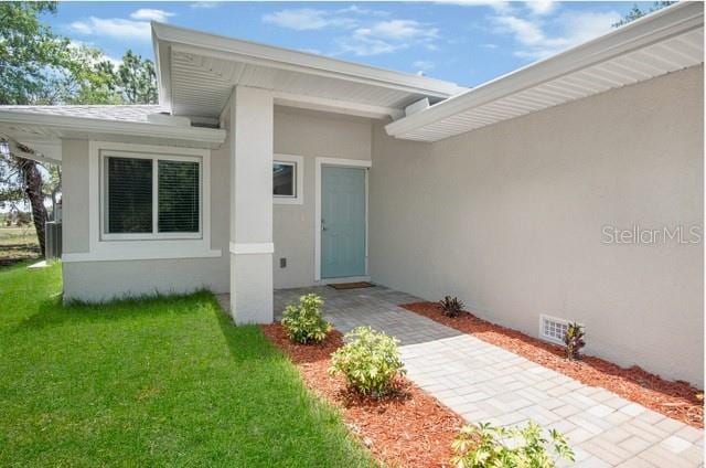 9471-9473 Agate St, Port Charlotte, FL 33981 - view of exterior entry featuring stucco siding and a lawn