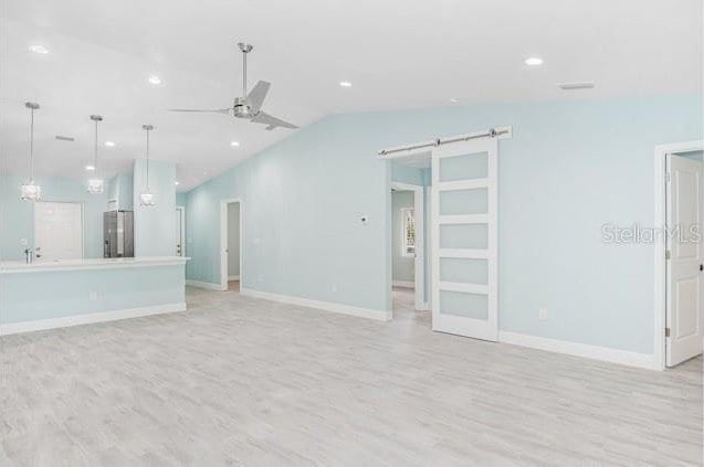 9471-9473 Agate St, Port Charlotte, FL 33981 - unfurnished living room featuring light wood-style flooring, a barn door, ceiling fan, vaulted ceiling, and recessed lighting