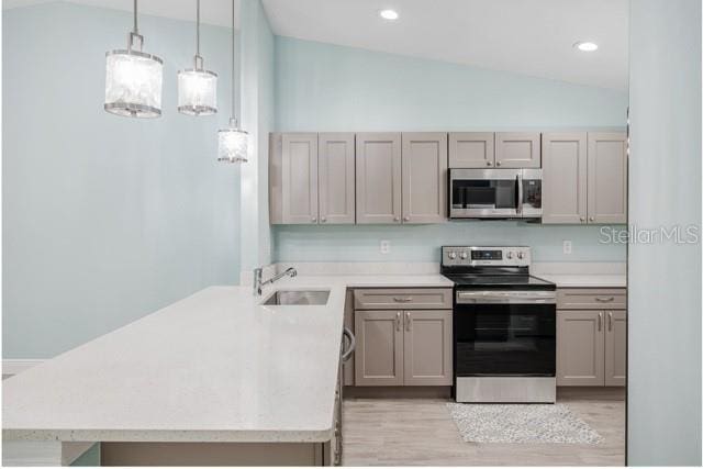9471-9473 Agate St, Port Charlotte, FL 33981 - kitchen featuring appliances with stainless steel finishes, lofted ceiling, light wood-type flooring, light countertops, and a peninsula