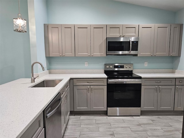 9471-9473 Agate St, Port Charlotte, FL 33981 - kitchen featuring appliances with stainless steel finishes, gray cabinetry, vaulted ceiling, light stone countertops, and light wood finished floors