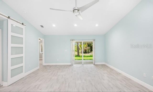 9471-9473 Agate St, Port Charlotte, FL 33981 - empty room featuring vaulted ceiling, wood finished floors, a barn door, recessed lighting, and ceiling fan