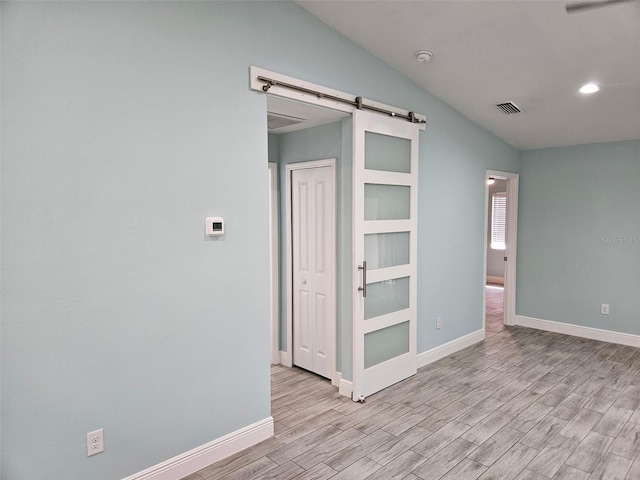 9471-9473 Agate St, Port Charlotte, FL 33981 - unfurnished room with a barn door, light wood-style flooring, a smoke detector, vaulted ceiling, and recessed lighting