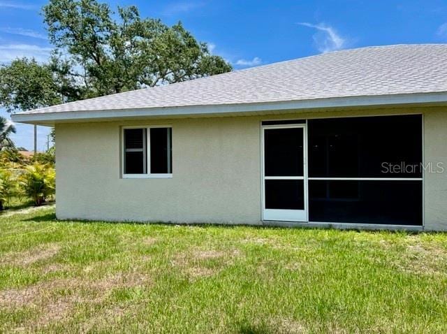 9471-9473 Agate St, Port Charlotte, FL 33981 - back of house featuring stucco siding, a yard, and roof with shingles