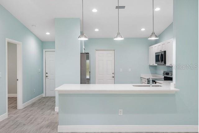 9471-9473 Agate St, Port Charlotte, FL 33981 - kitchen featuring stainless steel microwave, electric stove, light countertops, hanging light fixtures, and light wood-type flooring