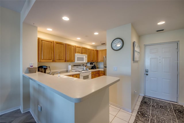 2090 Matecumbe Key Rd Unit 1202, Punta Gorda, FL 33955 - kitchen with white appliances, light countertops, a peninsula, recessed lighting, and brown cabinetry