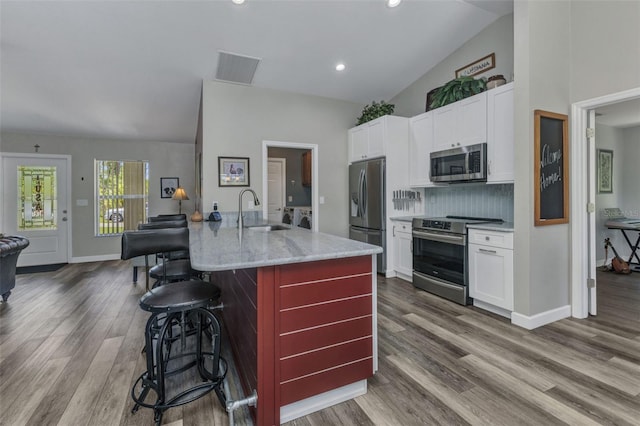 1445 Gauguin Rd, North Port, FL 34288 - kitchen with stainless steel appliances, lofted ceiling, a breakfast bar, dark wood-style floors, and white cabinets