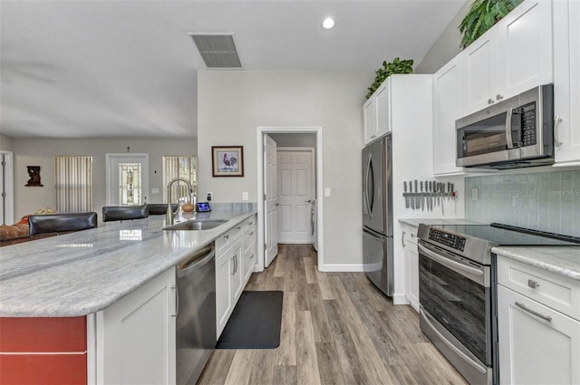 1445 Gauguin Rd, North Port, FL 34288 - kitchen with stainless steel appliances, a peninsula, white cabinets, backsplash, and light wood finished floors