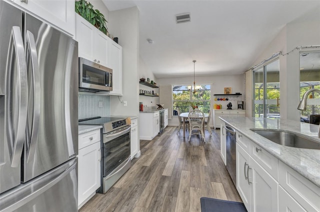 1445 Gauguin Rd, North Port, FL 34288 - kitchen with stainless steel appliances, white cabinets, backsplash, a chandelier, and wood finished floors