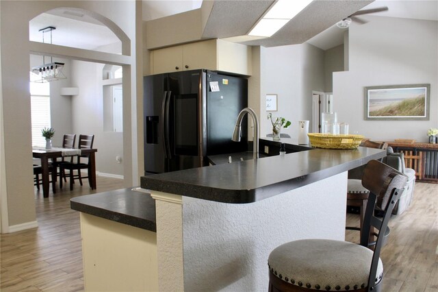 8039 Agate St, Port Charlotte, FL 33981 - kitchen featuring black fridge, light wood-style flooring, dark countertops, a breakfast bar, and a towering ceiling