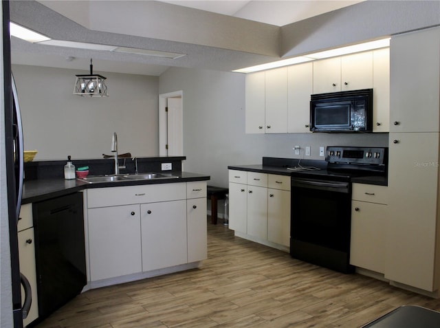 8039 Agate St, Port Charlotte, FL 33981 - kitchen featuring black appliances, dark countertops, light wood-style floors, white cabinetry, and decorative light fixtures