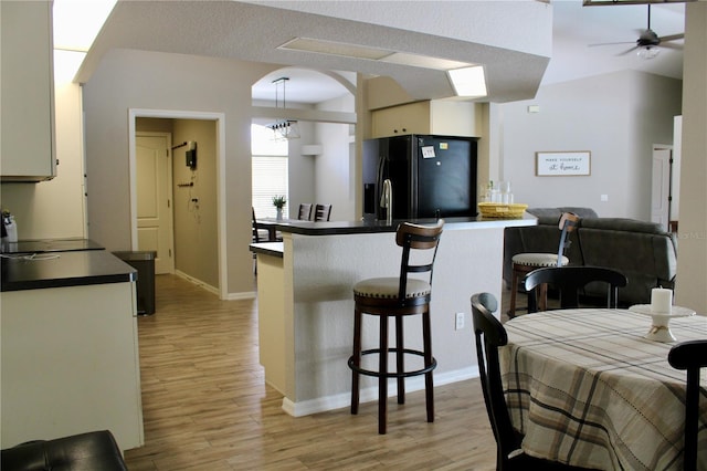 8039 Agate St, Port Charlotte, FL 33981 - kitchen with black fridge, dark countertops, light wood-style flooring, and a breakfast bar area
