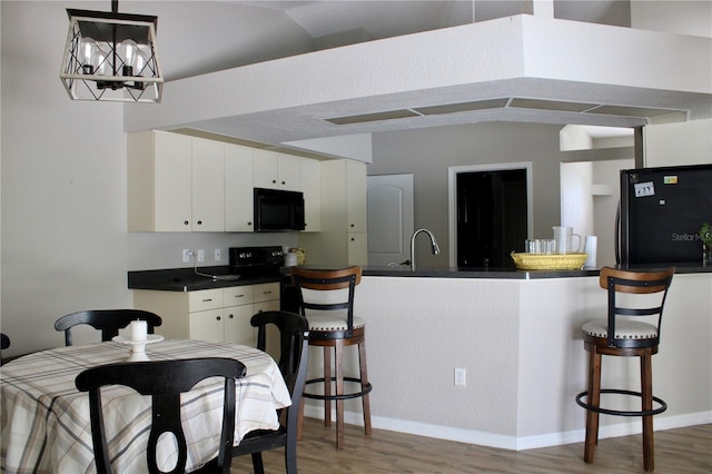 8039 Agate St, Port Charlotte, FL 33981 - kitchen featuring freestanding refrigerator, black microwave, dark countertops, and light wood-style floors