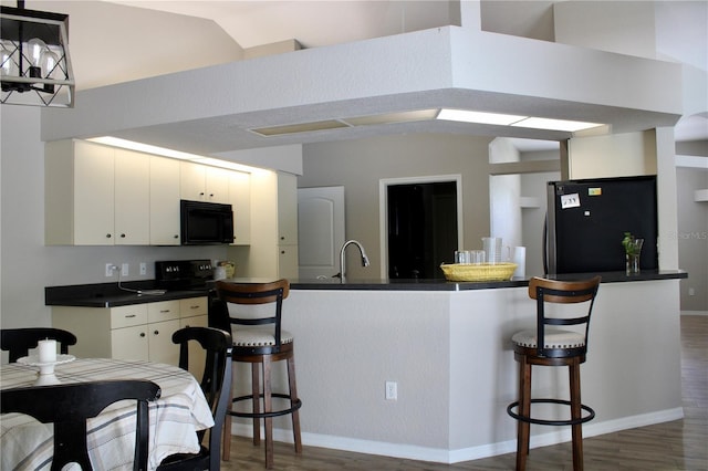 8039 Agate St, Port Charlotte, FL 33981 - kitchen with freestanding refrigerator, black microwave, dark countertops, and dark wood finished floors