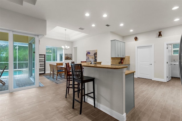 2453 Harbour Dr, Punta Gorda, FL 33983 - kitchen with a kitchen bar, light wood-style floors, recessed lighting, decorative backsplash, and pendant lighting