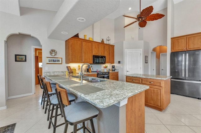 771 Rotonda Cir, Rotonda West, FL 33947 - kitchen featuring freestanding refrigerator, black microwave, a towering ceiling, arched walkways, and light tile patterned flooring