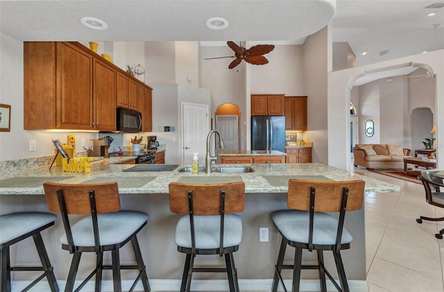 771 Rotonda Cir, Rotonda West, FL 33947 - kitchen with black appliances, a peninsula, a ceiling fan, arched walkways, and light stone counters